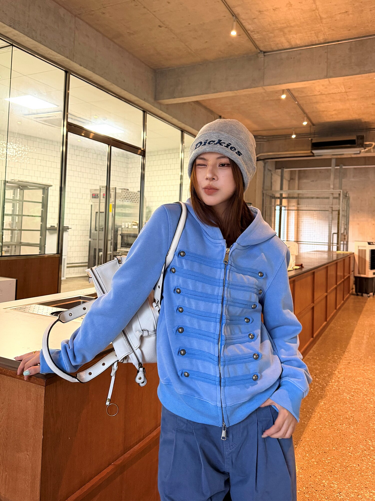 ブルーのミリタリー調ジップパーカーを着た女性モデル。胸に飾り紐7段と金属ボタン